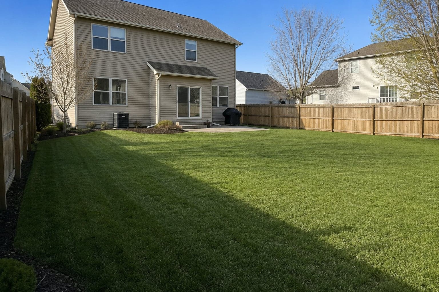A freshly cleaned-up backyard after a yard cleanup completed by First Class Property Services